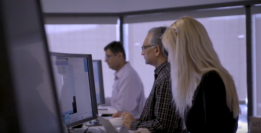 Contact center employees working at computers in an office environment, illustrating a collaborative and technology-driven workspace at Capital One.
